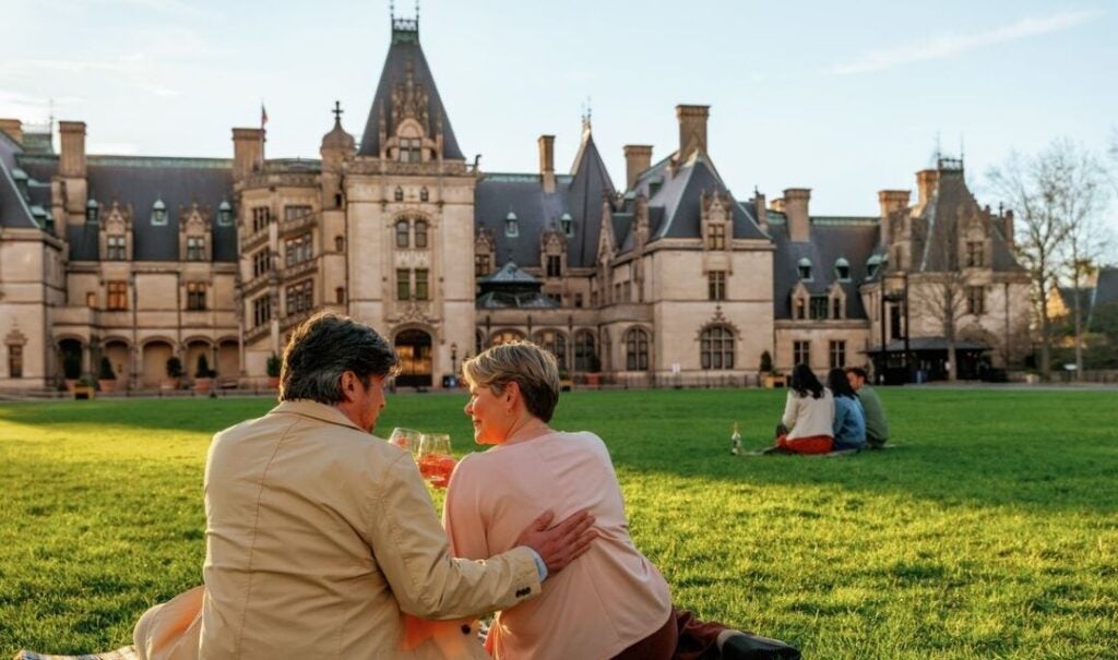 Couple drinking wine on the turf in front of Biltmore House