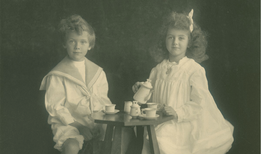 Archival photo of a young boy and girl having a tea party