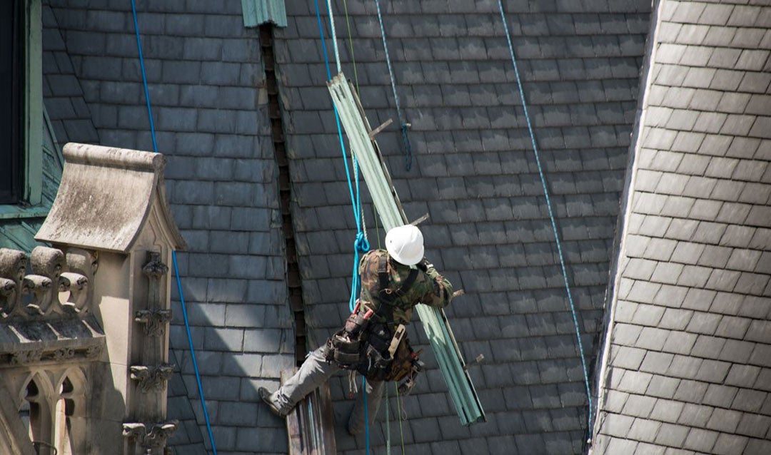 A worker removes a section of the original copper roofing