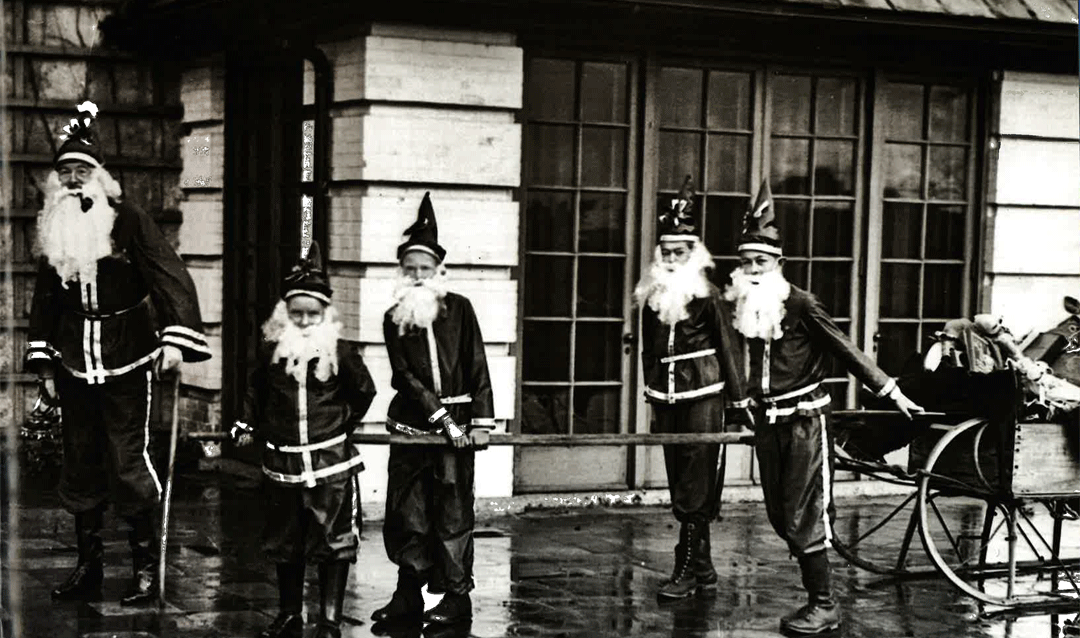 John Cecil dressed as Santa Claus with a group of children dressed as Santa's elves, ca. 1950