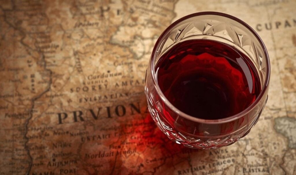 Glass of red wine over an antique map of Portugal.