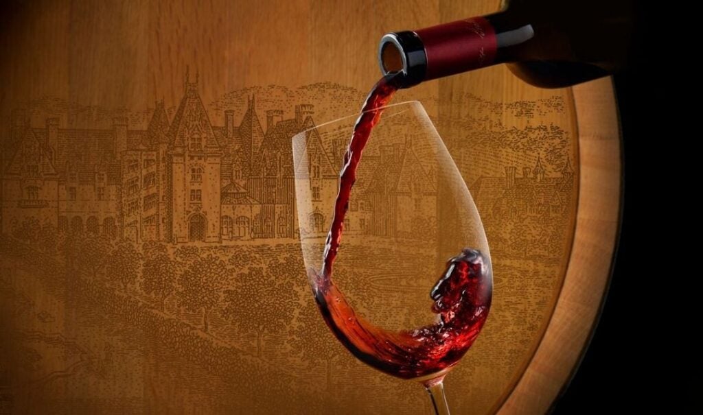 Red wine poured into a glass in front of a barrel with an image of Biltmore House.