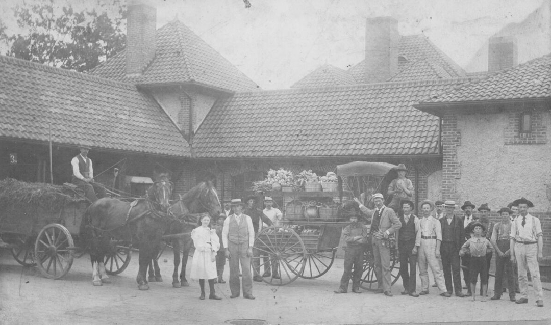 Archival photo of people and produce in front of the Market Gardener's Cottage at Biltmore