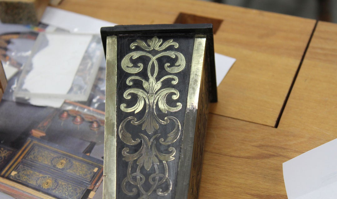 A decorative desk leg showing old and new brass marquetry