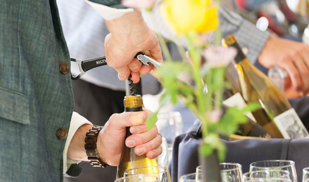 Man opens wine with corkscrew