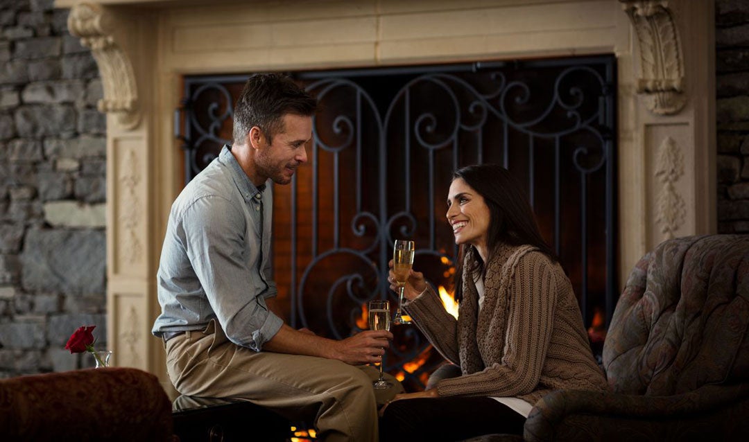 Couple with sparkling wine by a fireplace