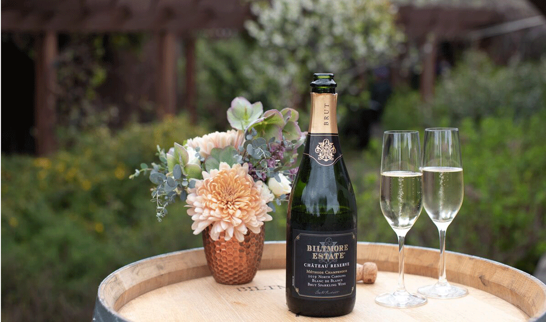 Bottle of Biltmore sparkling wine with a wine flute and flower arrangement