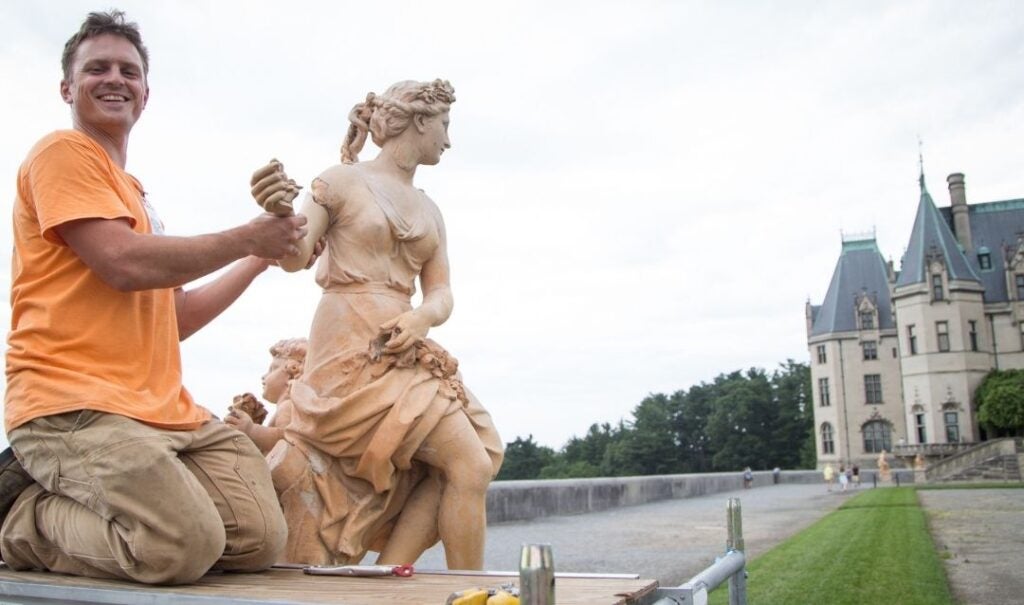 Artist holds the arm of a restored statue of Flora on the South Terrace of Biltmore House.