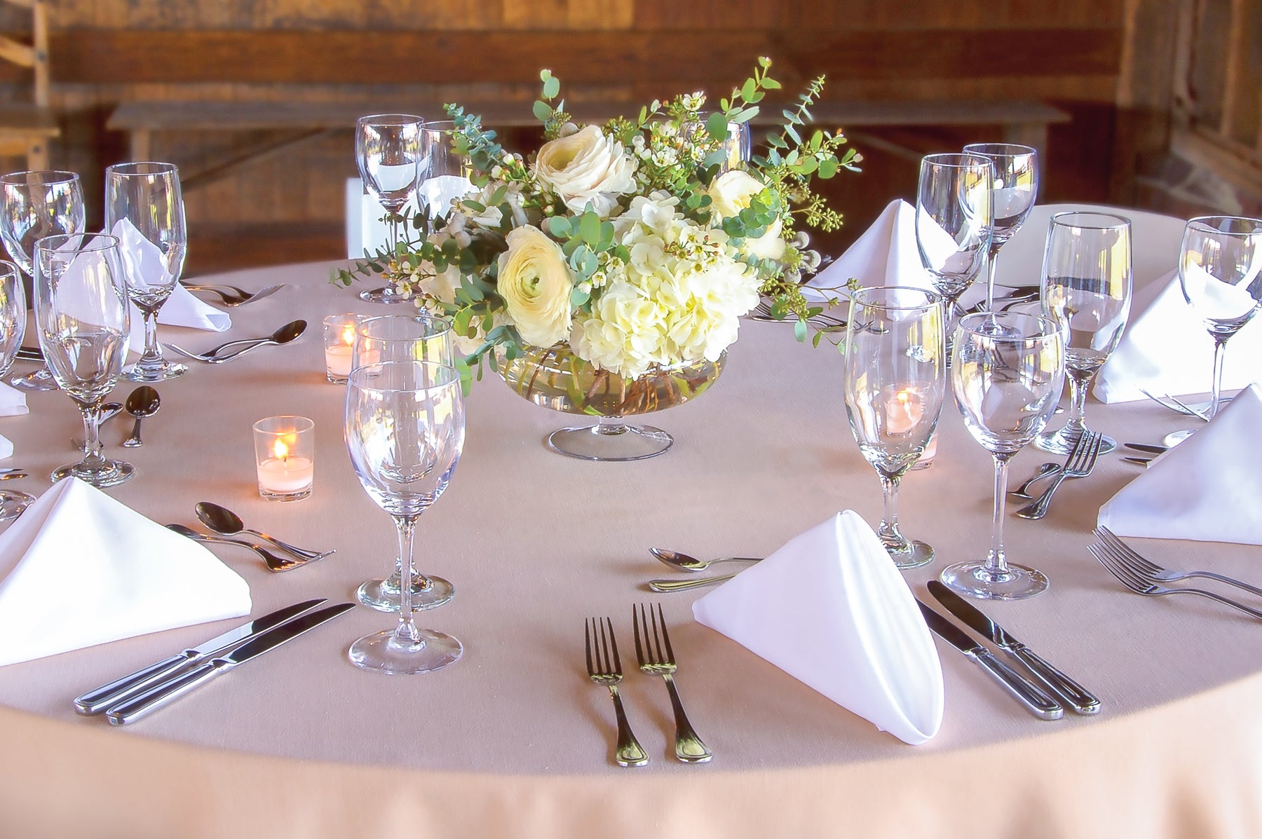 Dining table set with white linens and white flowers.
