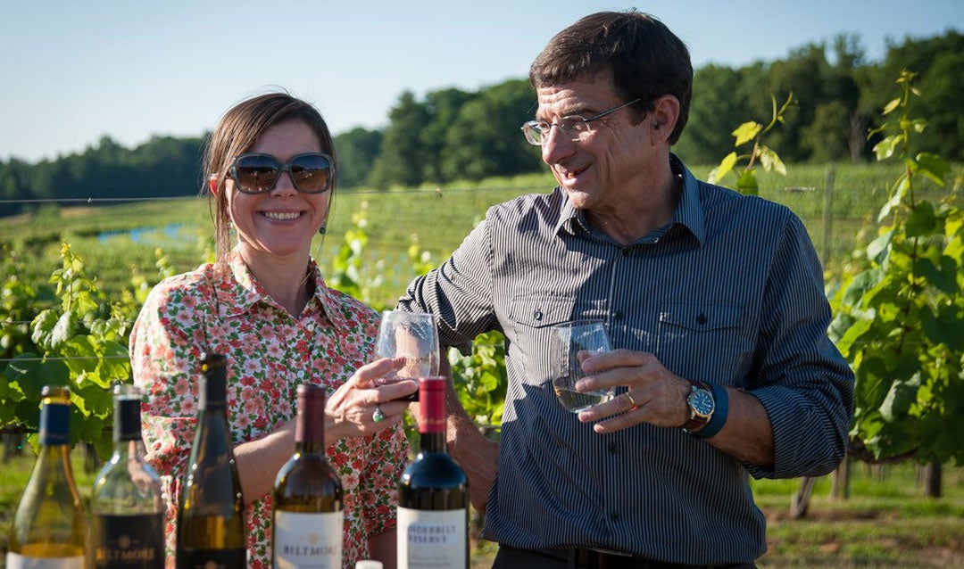 Sharon Fenchak and Bernard Delille enjoy a glass of wine in Biltmore's vineyard