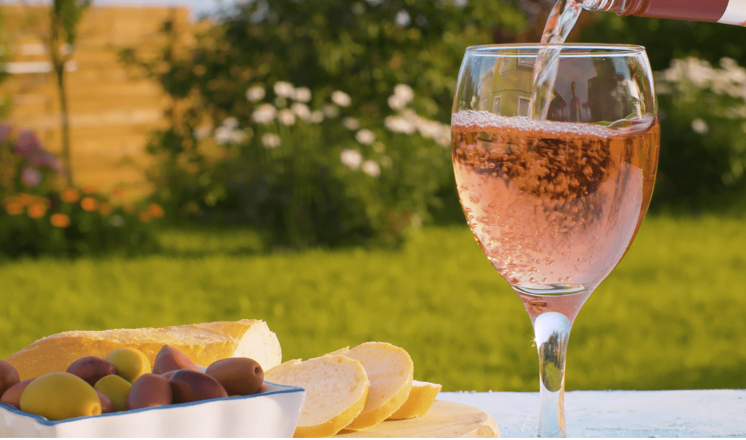 Glass of rosé wine with olives and bread.