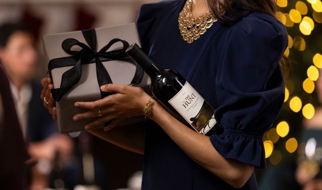 Woman holding a Christmas gift and a bottle of Biltmore wine.