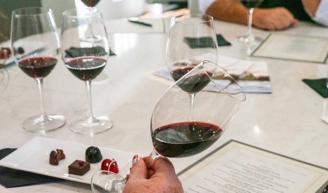 Red wine in a glass with a plate of chocolates.