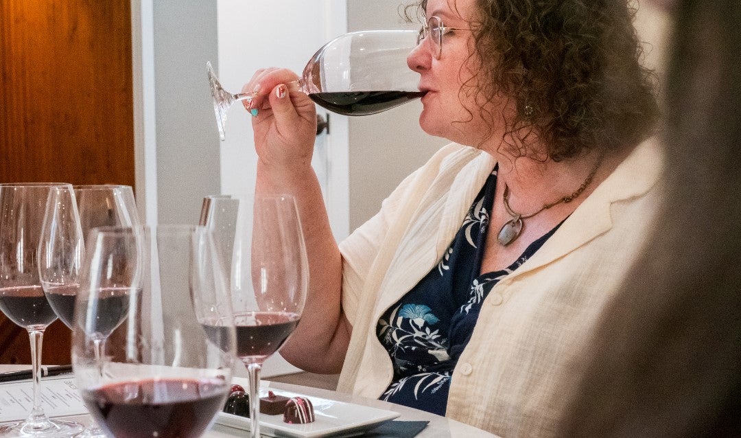 Woman sipping a glass of red wine.