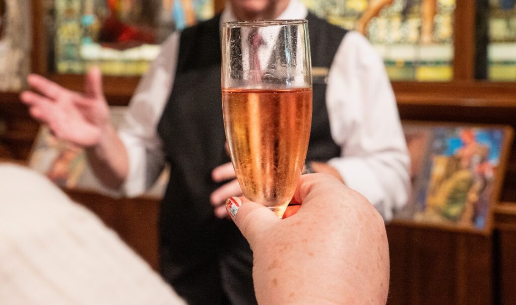 Person holding a flute of pink sparkling wine.
