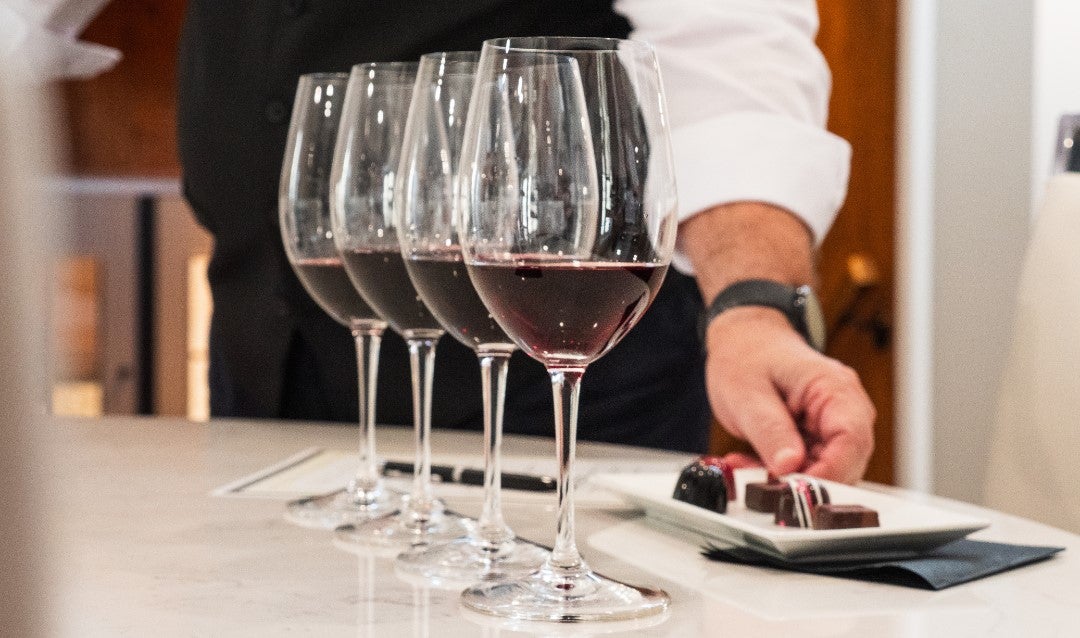 Glasses of red wine with a tray of chocolates.