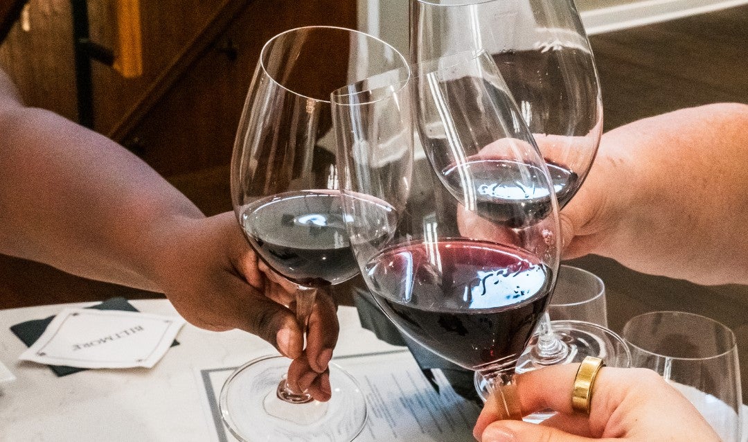 3 people toasting with red wine.