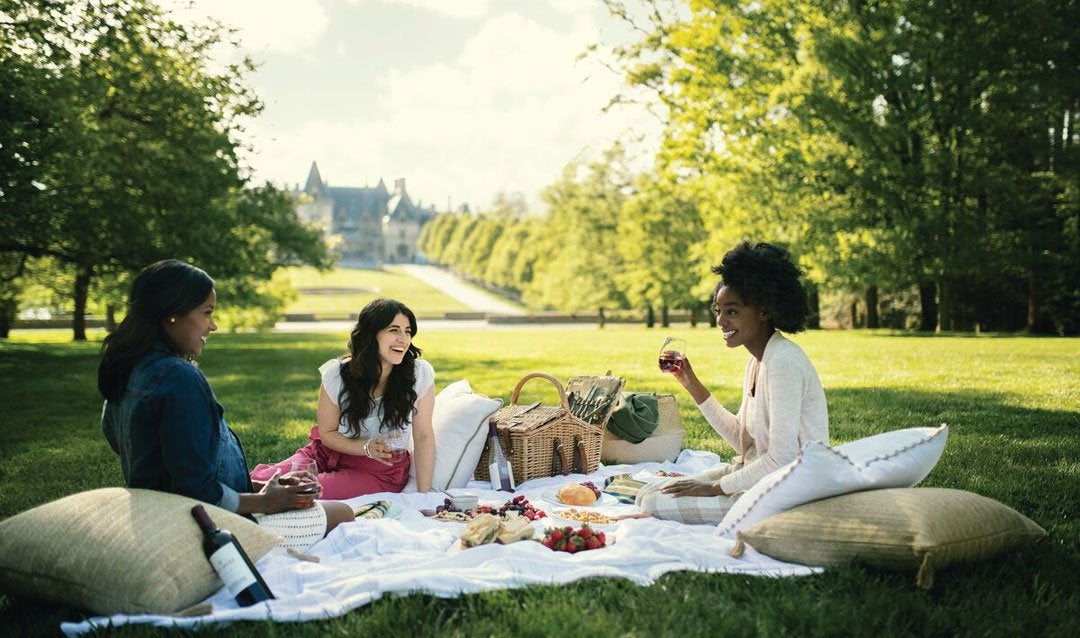Three women enjoy a picnic with a view of Biltmore House