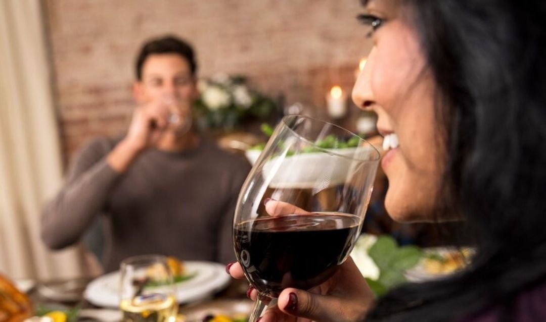 Man and woman drinking red wine at a table.