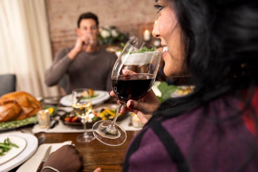 Man and woman drinking red wine at a table.