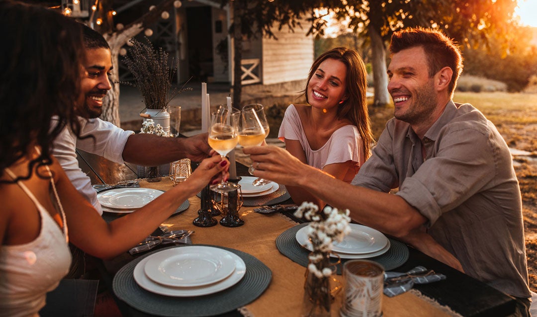 Two couples enjoying white wine outdoors