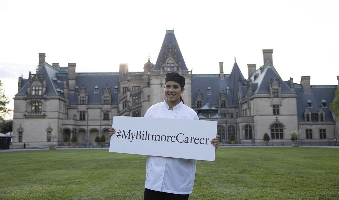 Culinary staff holds career sign in front of Biltmore House