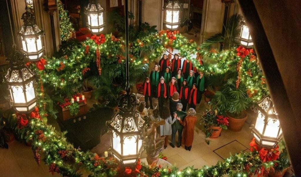 A choir with red and green scarves performs in the Winter Garden of Biltmore House