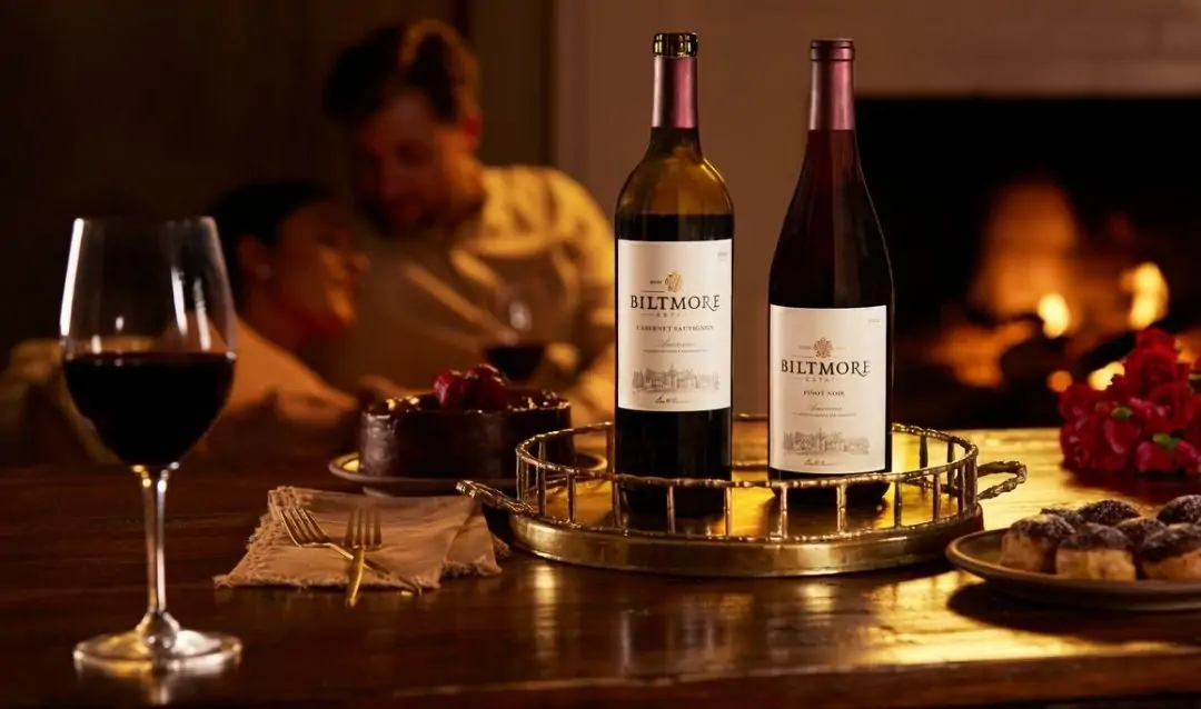 A couple pairing Biltmore wine and chocolates by the fireside.