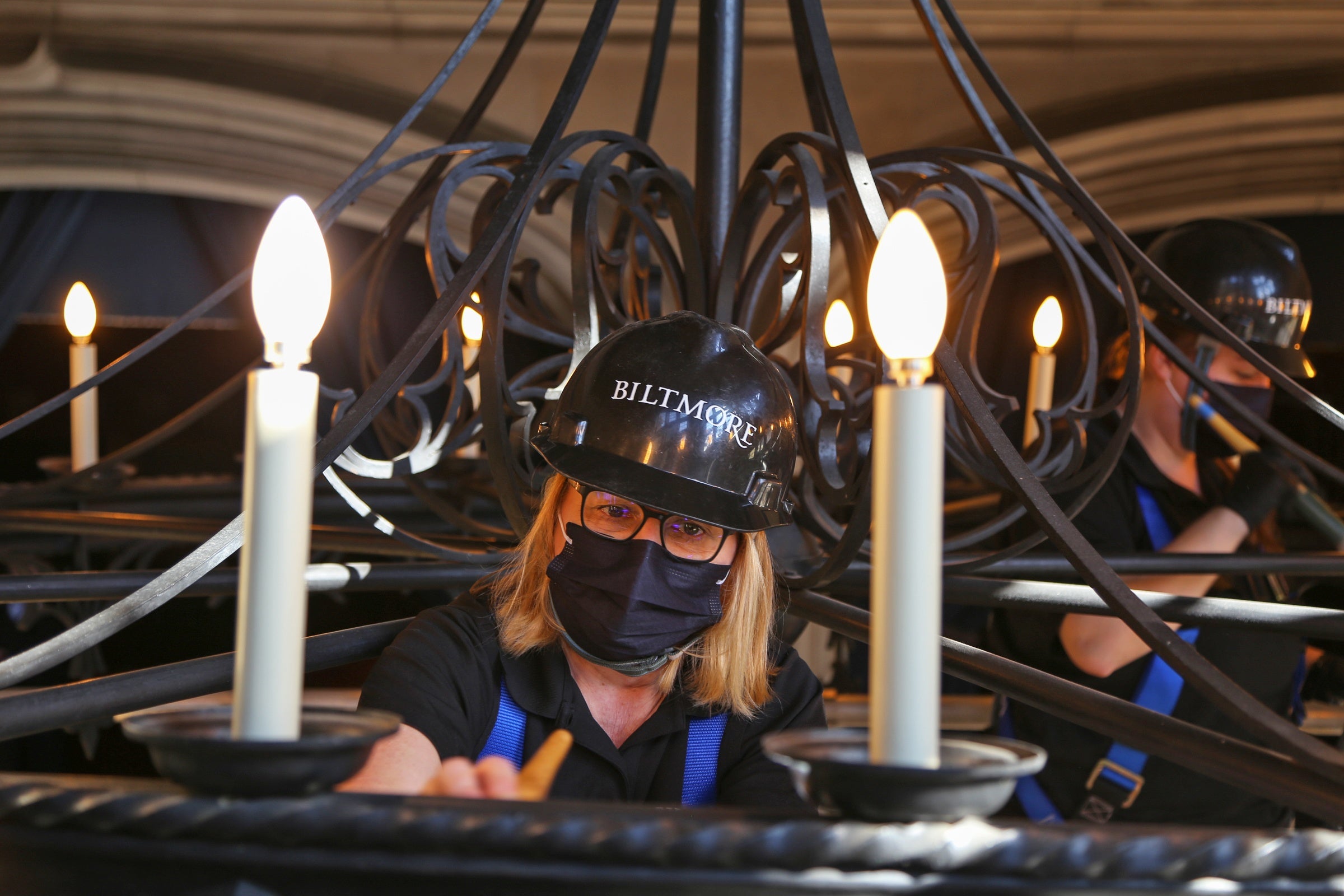 Close up of Biltmore housekeeping cleaning lightbulbs on Grand Staircase chandelier 