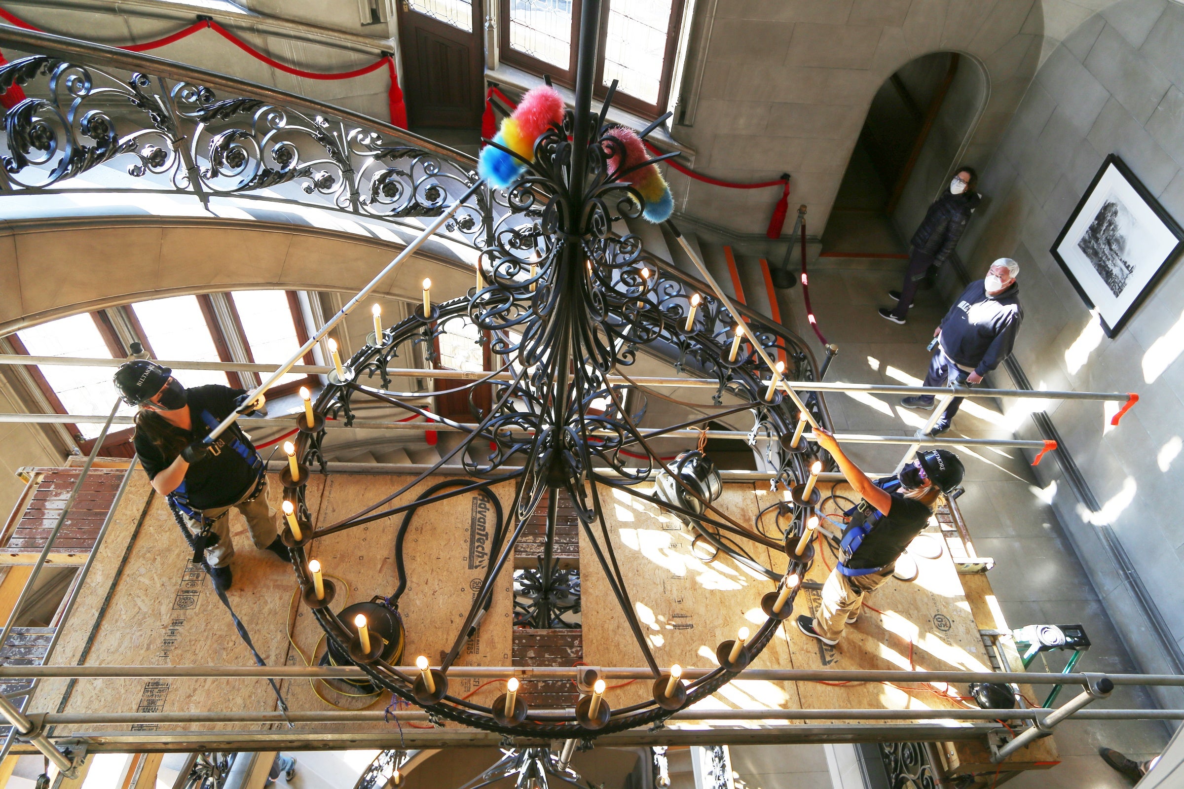 Photo of housekeepers cleaning Biltmore House's Grand Staircase chandelier