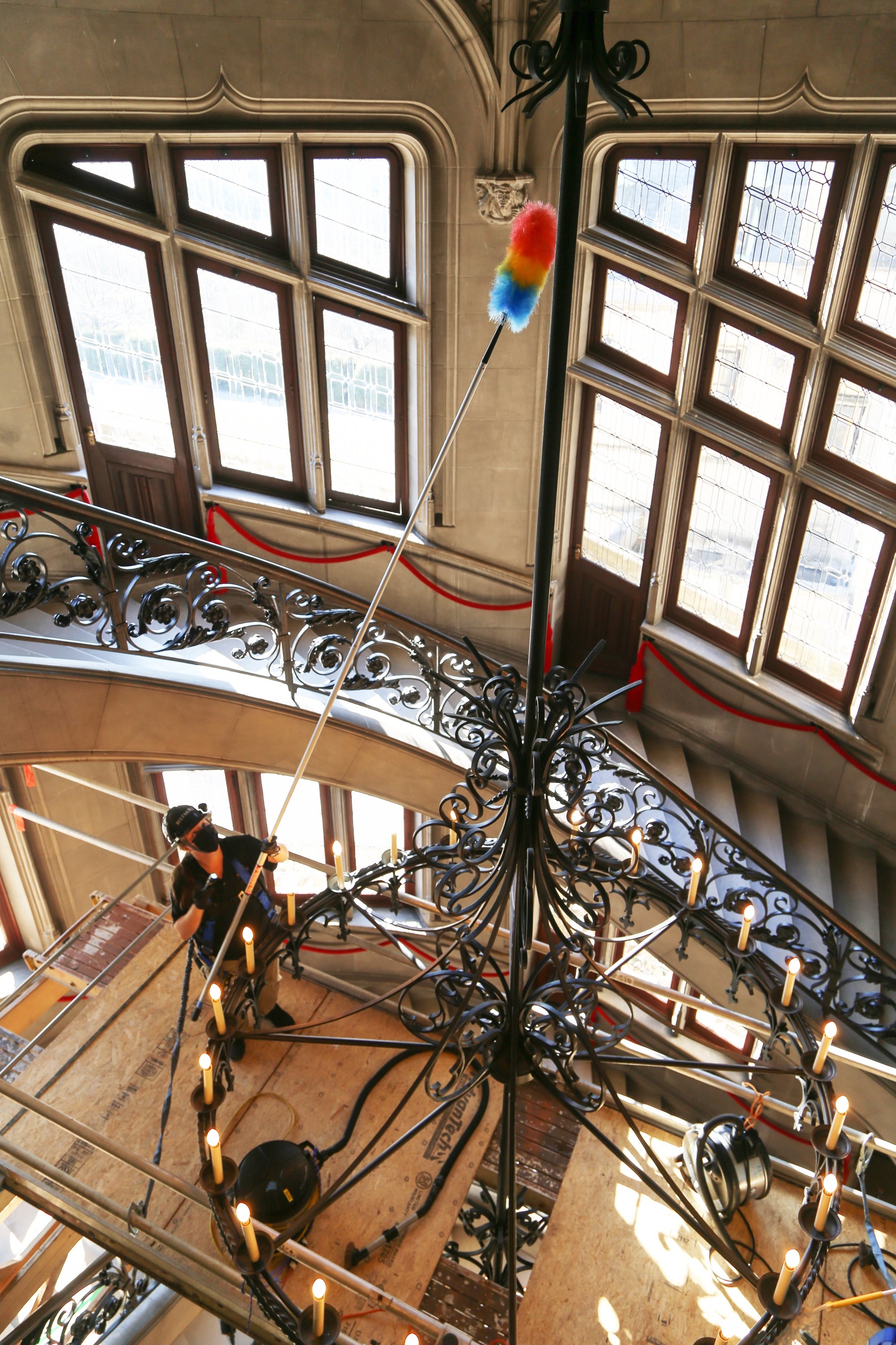 Biltmore housekeeping extends long duster to clean high up details of the grand staircase chandelier 