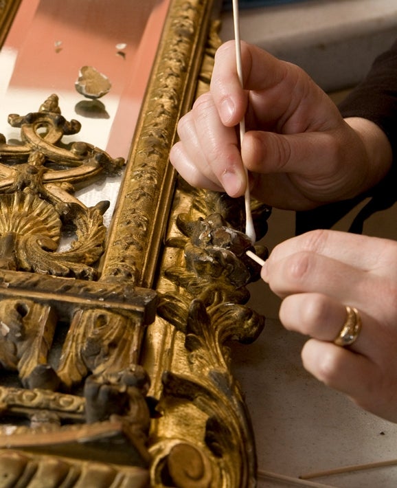 conservator cleans and repairs mirror frame