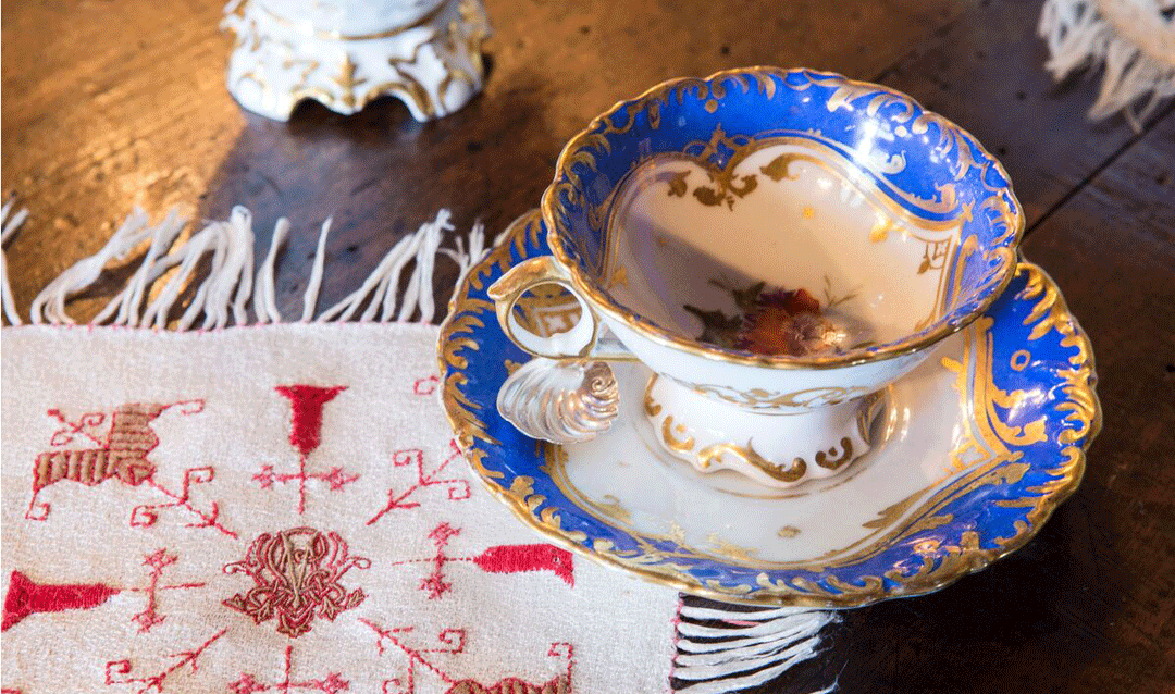 Blue and gold tea set with a monogrammed linen cloth.