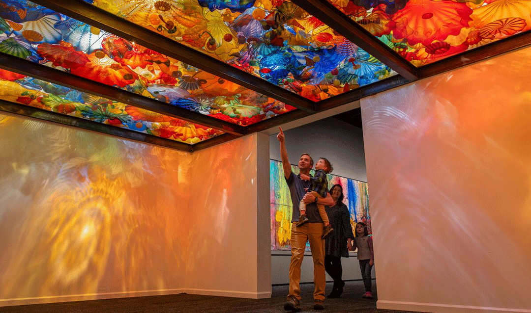 Man holding a child looks at Persian Ceiling installation for Chihuly at Biltmore.