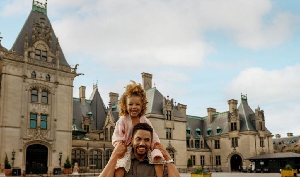 Father with daughter on his shoulders in front of Biltmore House