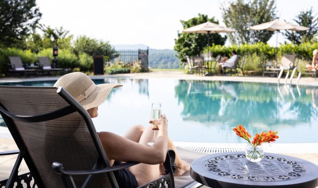 Woman sipping sparkling wine by the pool at The Inn on Biltmore Estate