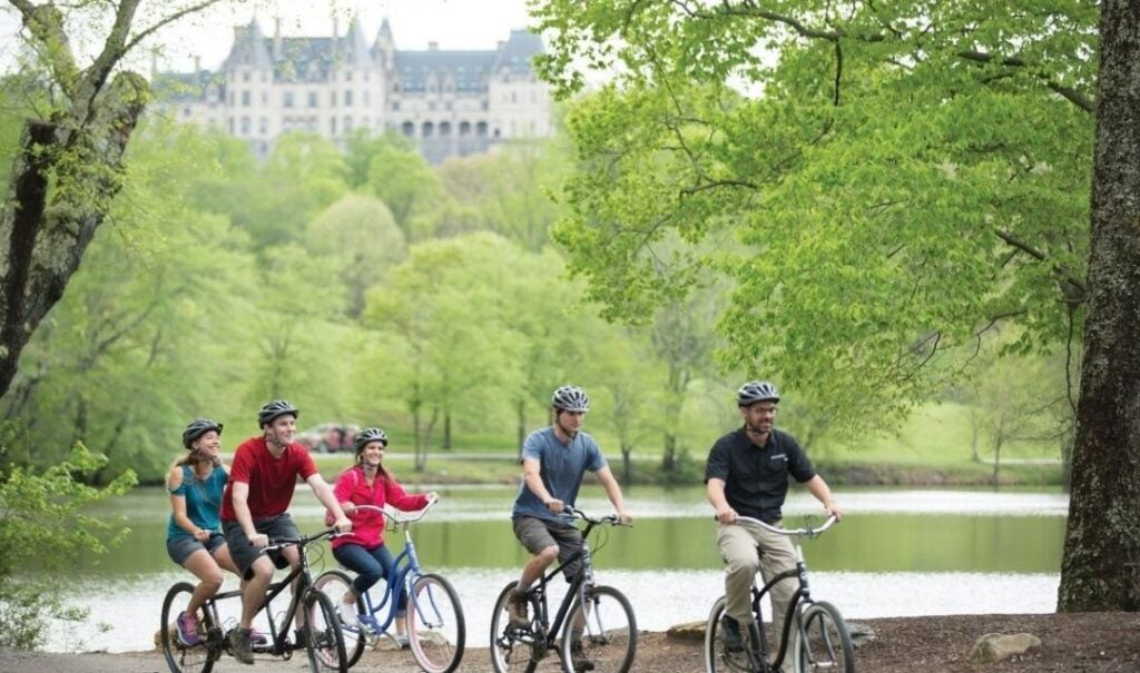Group biking around the Lagoon at Biltmore with Biltmore House in the background