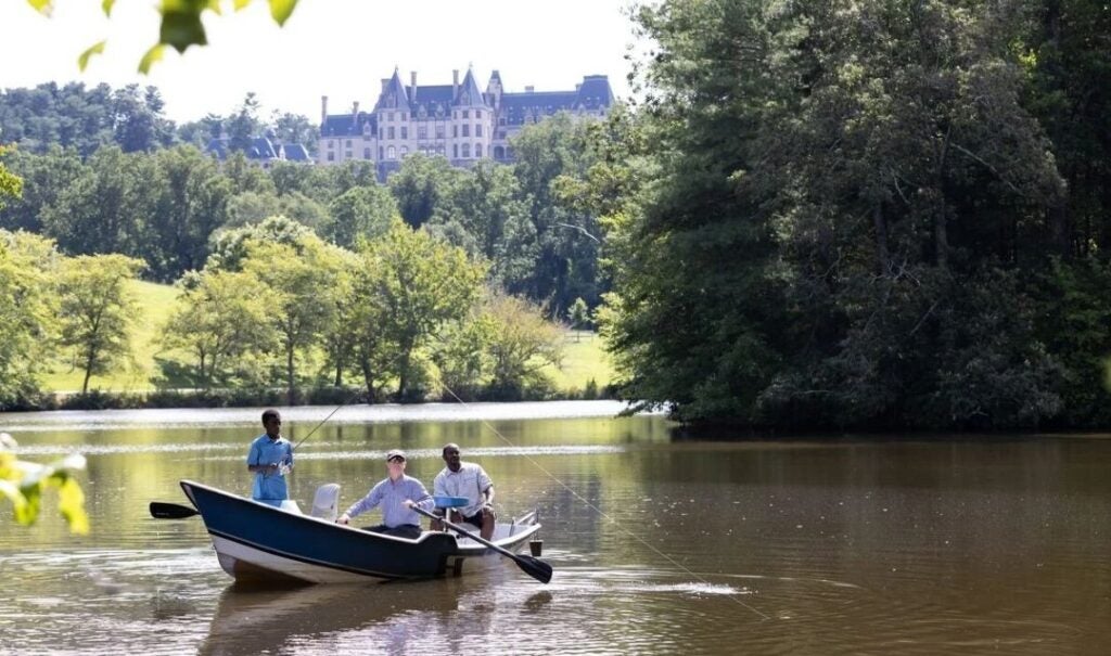 Guests enjoy a guided fly-fishing lesson on the Lagoon with Biltmore House in the background.