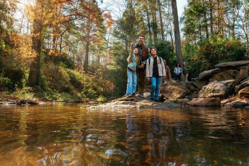 Family surrounded by fall color at the edge of the water below the spillway at Biltmore