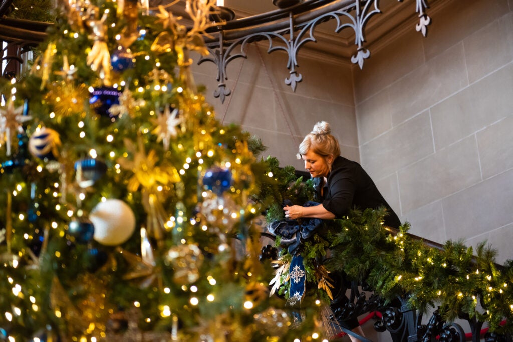 A member of Biltmore's Floral team adds Christmas decor to the Grand Staircase.
