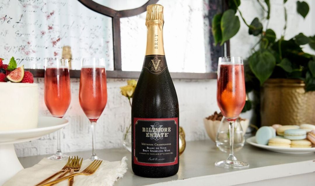 Bottle and glasses of Biltmore Estate Blanc de Noir sparkling wine and a plate of macarons.