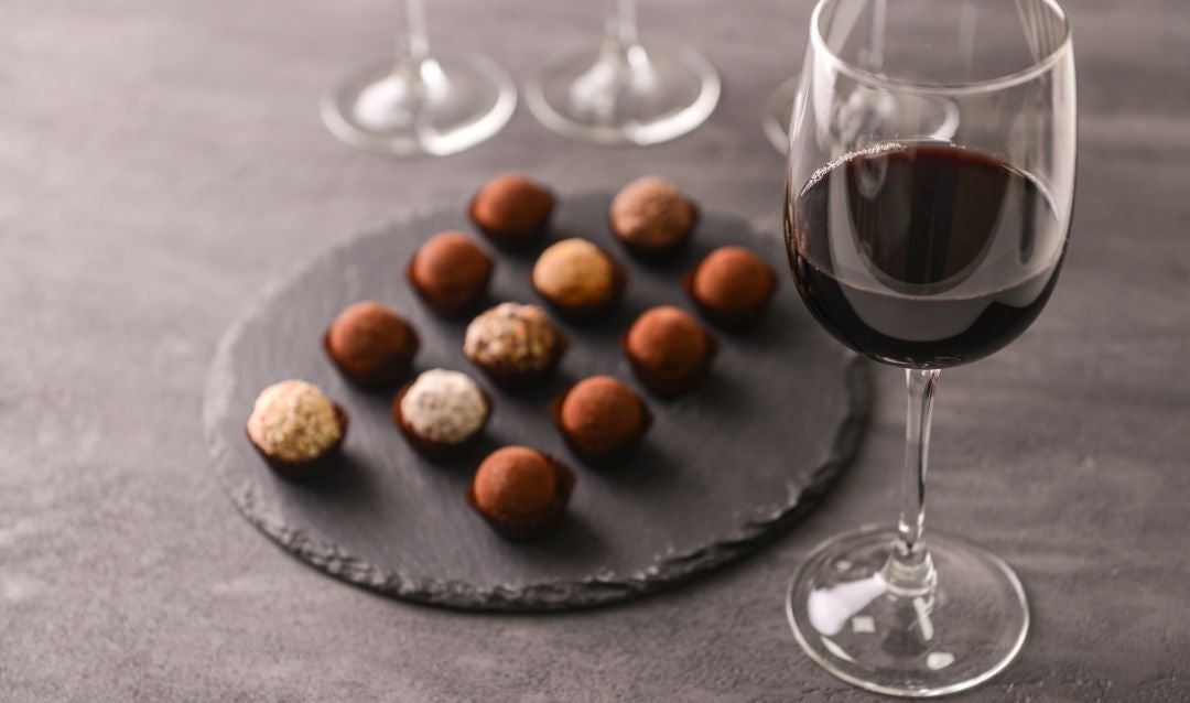 Glass of red wine with a plate of chocolate truffles.