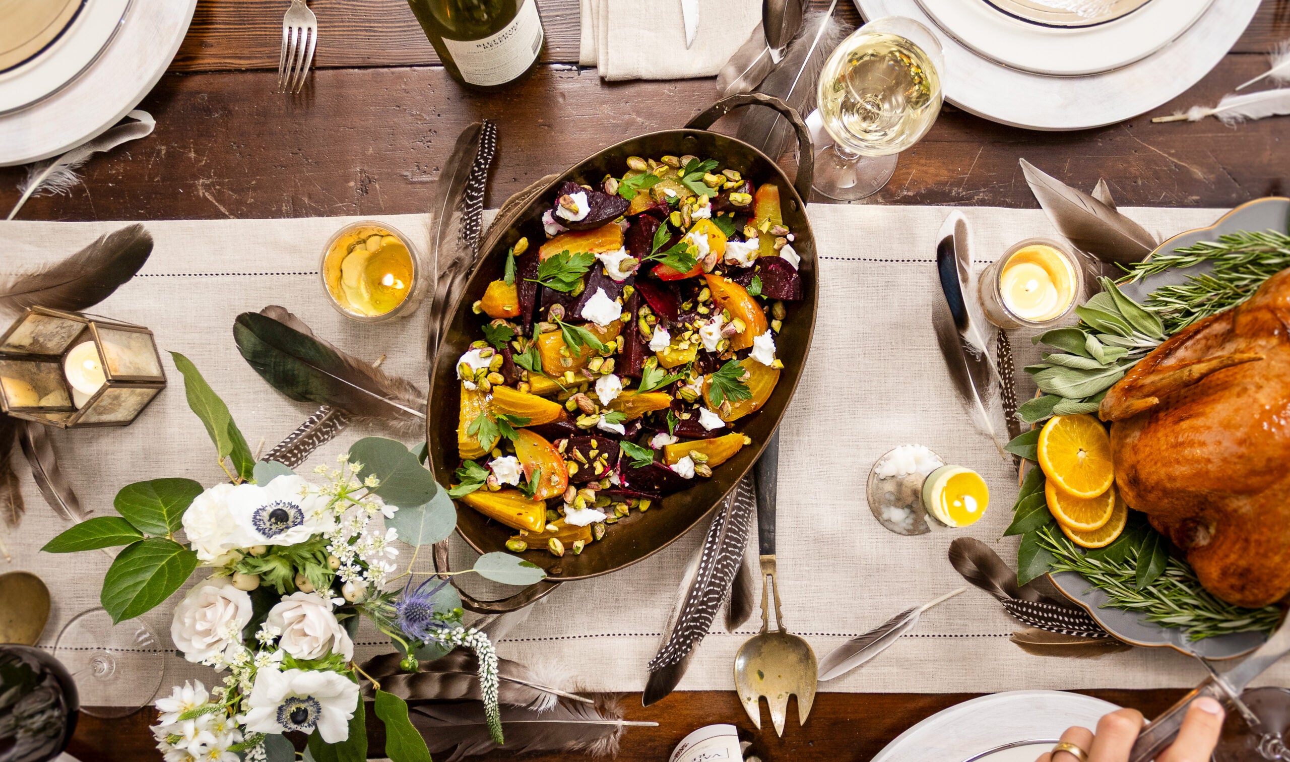 Roasted beet salad served in oval dish surrounded by holiday dishes and wines.