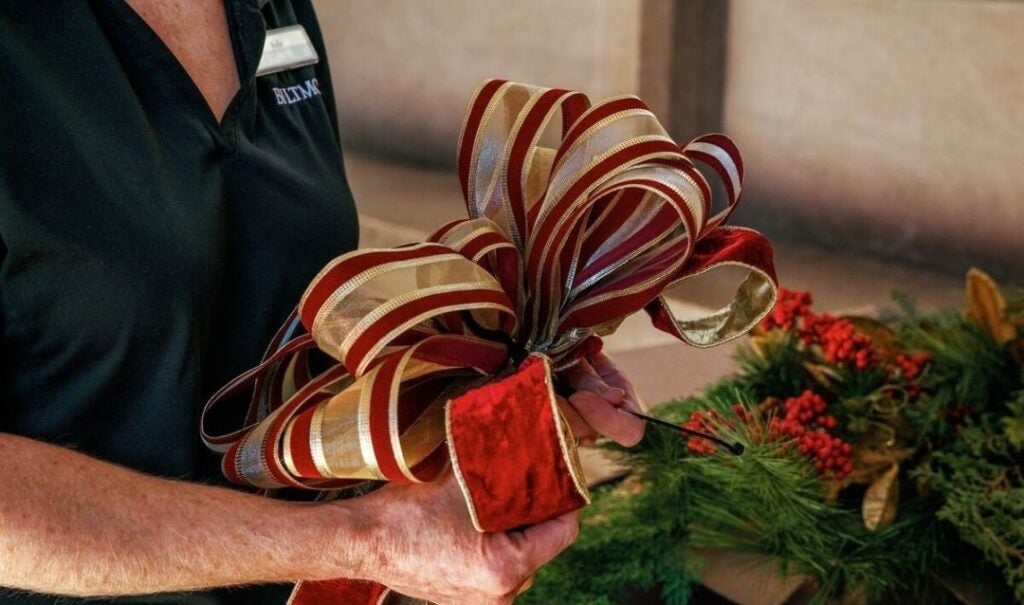 Wiring a hand-tied Christmas bow in place at Biltmore
