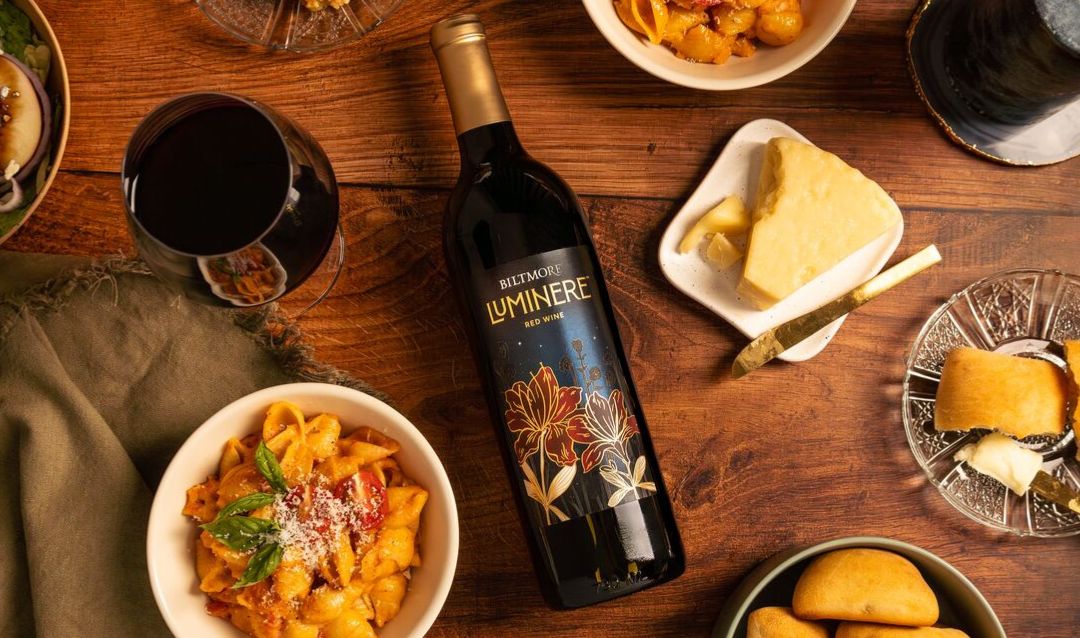 Bottle of Luminere Red Wine on a table with food.