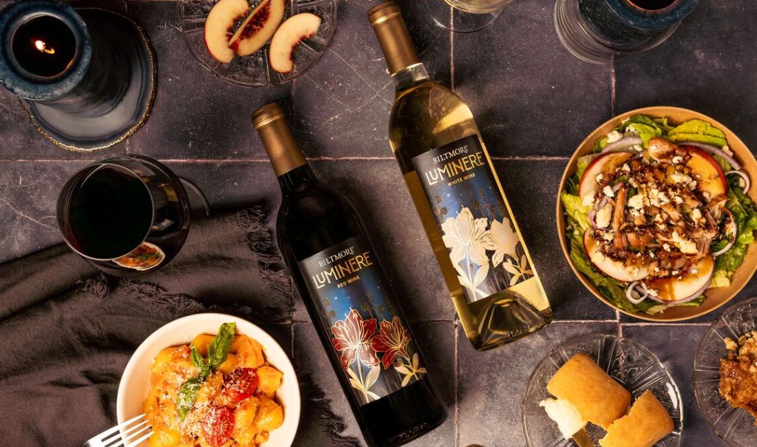 Bottles of Red and White Luminere wine on a table with food.