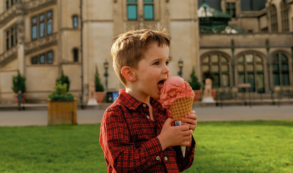 boy eating a big ice cream cone in front of Biltmore House