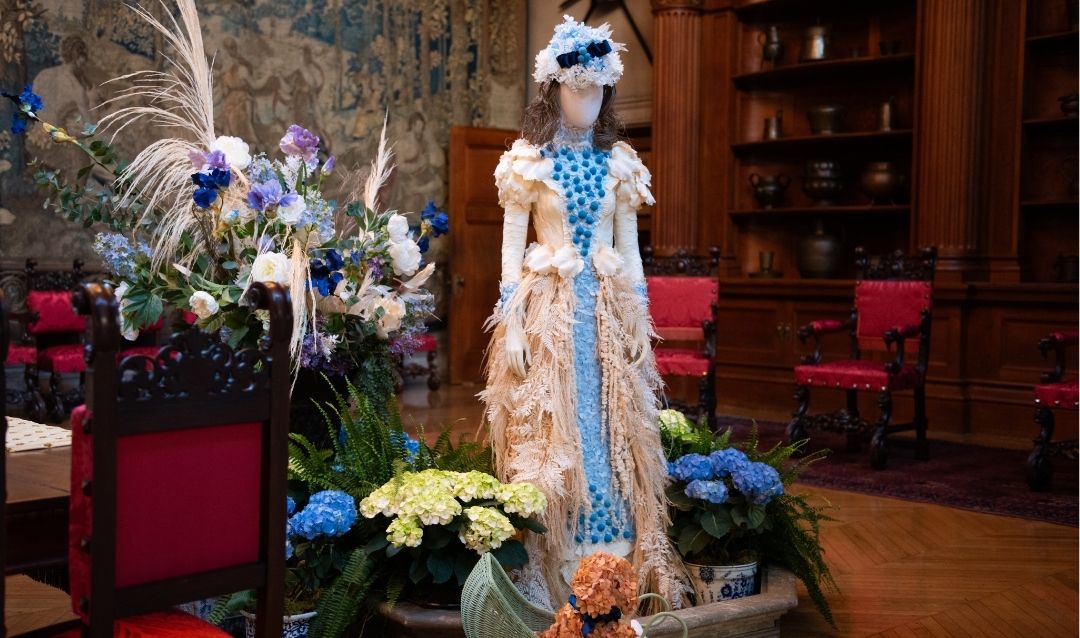 A floral mannequin in the Banquet Hall has a puppy made of hydrangeas in the doll carriage at her feet.