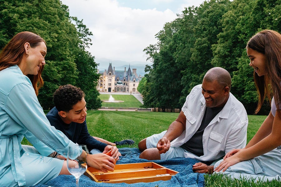 Family playing board game on Biltmore Estate lawn.