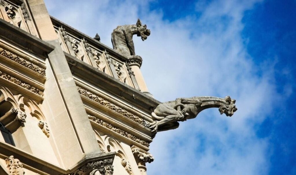 A gargoyle and a grotesque on the roof of Biltmore House against a blue sky